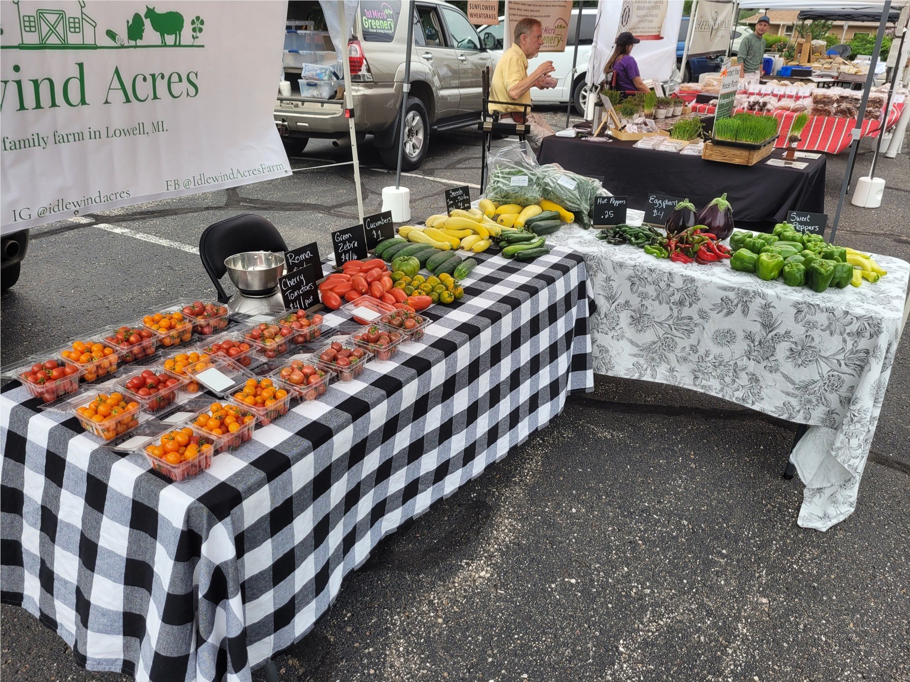 Our L-shaped farmers market display, with two produce-filled tables and the Idlewind Acres banner.