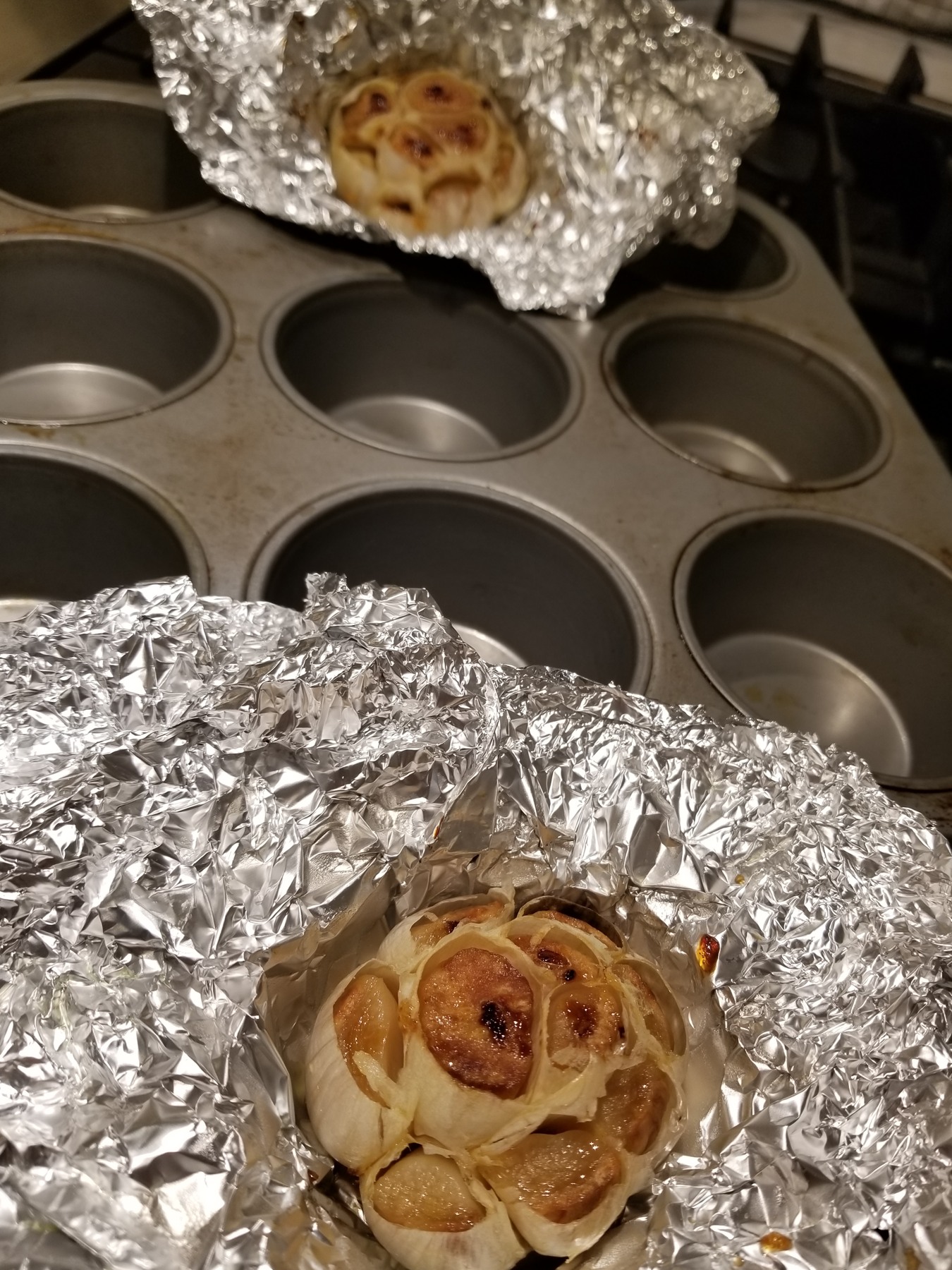 Whole roasted garlic bulbs nestled in aluminum foil.