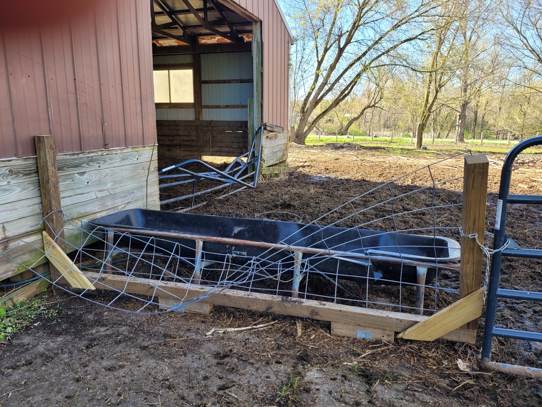Bent fencing and a collapsed metal gate beside the barn.